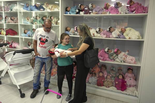 A family shops for a hyper-realistic reborn babydoll at a shopping mall in Campinas, Brazil, Saturday, May 24, 2025. (AP Photo/Andre Penner)