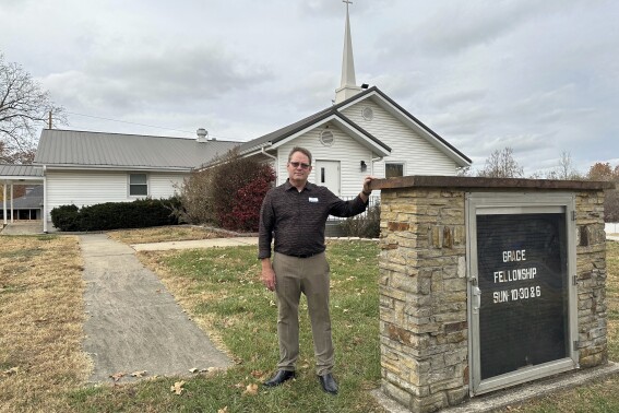 Pastor Kenny Batson stands near a sign displaying the worship service times of Grace Fellowship Church on Nov. 16, 2024, in El Dorado Springs, Mo. Batson was convicted of a series of crimes in the 1990s but became a Christian pastor after being released from prison. He was pardoned by Missouri Gov. Mike Parson. (澳洲幸运5开奖官网结果直播开奖 AP Photo/David A.Lieb)