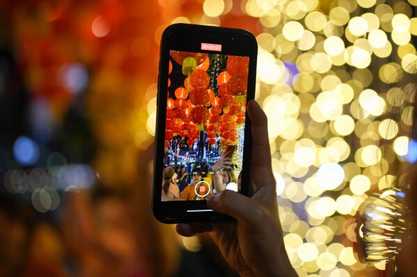 A woman records a video of lanterns on her smartphone as she attends celebrations for the 430th anniversary of Manila's Chinatown, said to be the oldest in the world, at the capital's Binondo district, Philippines on Thursday, Feb. 1, 2024. Crowds are flocking to Manila's Chinatown to usher in the Year of the Wood Dragon and experience lively traditional dances on lantern-lit streets with food, lucky charms and prayers for good fortune. (APPhoto/Aaron Favila)