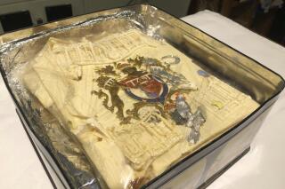 The tin containing plastic wrapped icing of a slice of cake from one of the 23 official wedding cakes made for the Royal Wedding of Prince Charles and Lady Diana Spencer on Wednesday July 29, 1981, which has fetched 1,850 pounds (2,565 dollars US) at auction at Dominic Winter Auctioneers in Cirencester, England, Wednesday Aug. 11, 2021. (Claire Hayhurst/PA via AP)