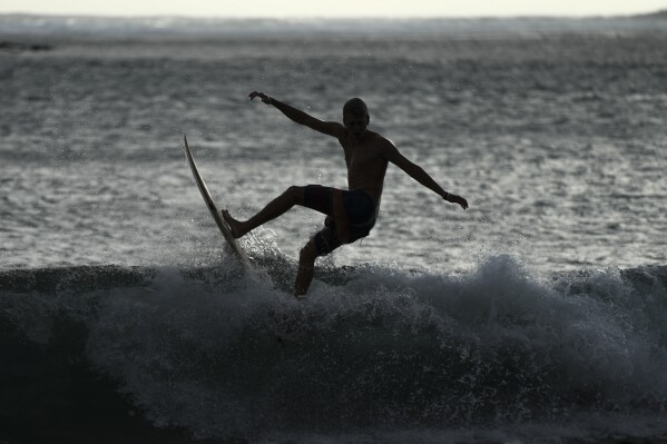 A surfer is silhouetted in Teahupo'o, Tahiti, French Polynesia, Sunday, Jan. 14, 2024. (AP Photo/Daniel Cole)