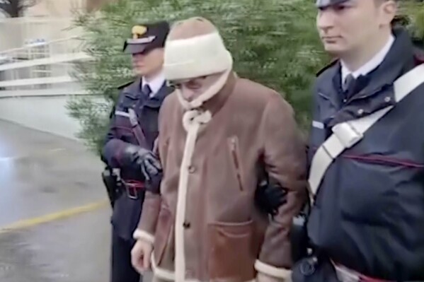 This image taken from an Italian Carabinieri handout video dating Jan. 16, 2023 shows Matteo Messina Denaro, center, a top Mafia boss, being escorted from a Carabinieri police station shortly after his arrest, in Palermo, southern Italy. Messina Denaro, a convicted mastermind of some of the Sicilian Mafia’s most heinous slayings, died on Monday, Sept. 25, 2023, in a hospital prison ward, several months after being captured as Italy’s No. 1 fugitive and following decades on the run, Italian prosecutors said. (Carabinieri via AP)