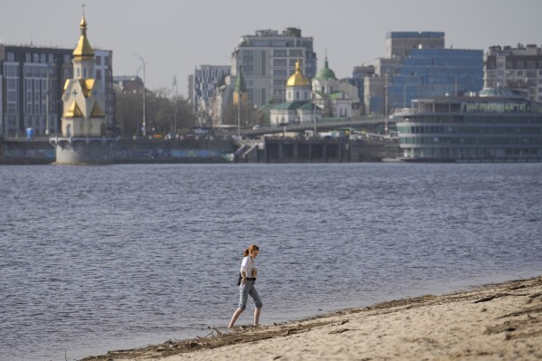 Một người phụ nữ tận hưởng một buổi chiều ấm áp bên bờ sông Dniepr ở Kyiv, Ukraine, Thứ Ba, ngày 2 tháng 4 năm 2024. (Ảnh AP / Vadim Ghirda)
