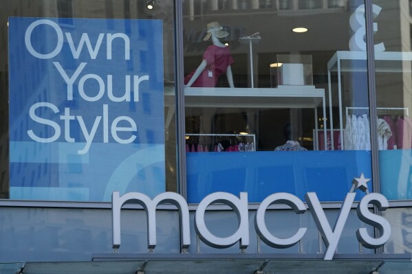 FILE - Signs hang from a Macy's store in San Francisco, April 18, 2023. Macy's is accelerating the expansion of its small-format stores as it looks to meet the needs of shoppers looking for more convenient locations. The department store said Tuesday, Oct. 3, 2023, that it aims to add up to 30 new small-format locations through fall 2025, bringing the total number of such stores to approximately 42. The next round of expansion begins in the fall of 2024. (AP Photo/Jeff Chiu, File)