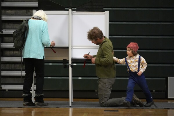 Oliver Paradee accompanies his father, Andrew Paradee, as he fills out his ballot in the primary election, Tuesday, March 5, 2024, in Stowe, Vt. (AP Photo/Robert F. Bukaty)