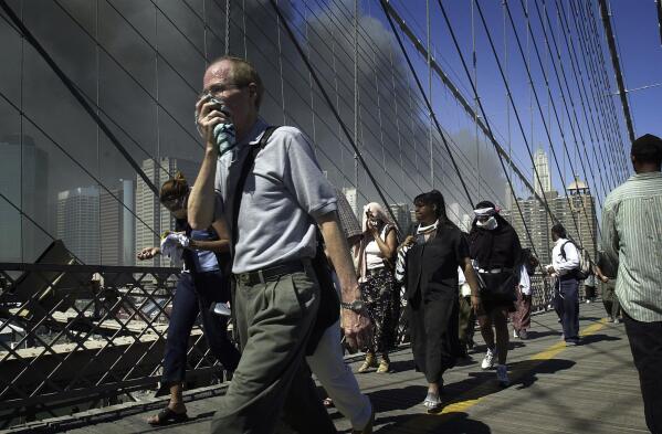 People walk over New York's Brooklyn Bridge from Manhattan to Brooklyn following the collapse of both World Trade Center towers on Sept. 11, 2001. (AP Photo/Mark Lennihan)