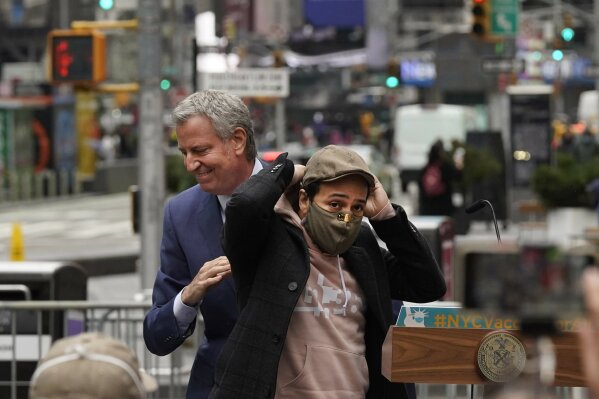 Actor Lin-Manuel Miranda, right, and New York Mayor Bill de Blasio, pass each other at the podium before Miranda's remarks in Times Square, after they toured the grand opening of a Broadway COVID-19 vaccination site intended to jump-start the city's entertainment industry, in New York, Monday, April 12, 2021. (AP Photo/Richard Drew)