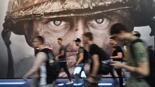 FILE - Visitors passing an advertisement for the video game 'Call of Duty' at the Gamescom fair for computer games in Cologne, Germany, Aug. 22, 2017. Microsoft has signed an agreement with Sony to keep the “Call of Duty” video game series on PlayStation following the tech giant’s acquisition of the video game maker Activision Blizzard. The announcement was made Sunday, July 16, 2023 in a Twitter post by Phil Spencer, who heads up Microsoft’s Xbox. (AP Photo/Martin Meissner, File)