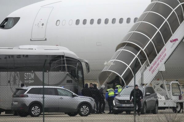 Los hombres abordan el avión inmovilizado por la policía en el aeropuerto de Vatry, el lunes 25 de diciembre de 2023 en Vatry, este de Francia.  (Foto AP/Christophe Ena)