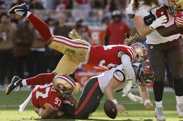 Tampa Bay Buccaneers quarterback Baker Mayfield, bottom right, fumbles while sacked by San Francisco 49ers defensive end Nick Bosa (97) and linebacker Fred Warner during the first half of an NFL football game in Santa Clara, Calif., Sunday, Nov. 19, 2023. The 49ers recovered the ball. (AP Photo/Josie Lepe)