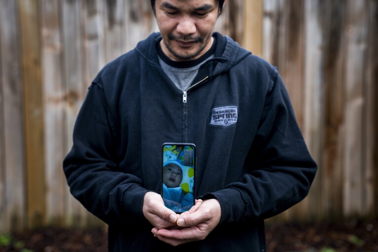 Seafarer Norberto Cabrela stands for a portrait while on a video call with his infant son, who he had not been able to meet in person, at a temporary rental house in Lacey, Wash., on Tuesday, Jan. 30, 2024. (AP Photo/Lindsey Wasson)