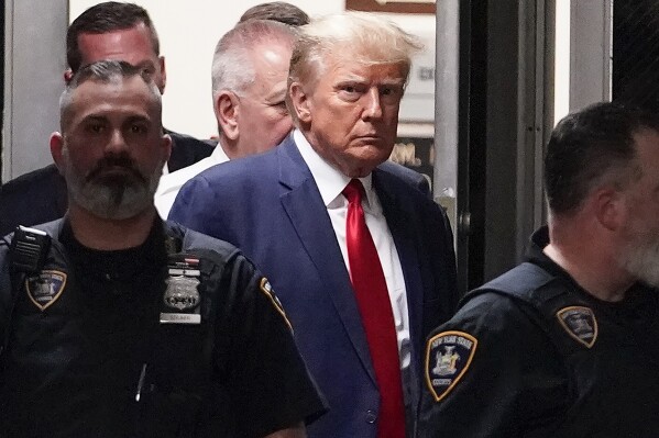 FILE - Former President Donald Trump is escorted to a courtroom, April 4, 2023, in New York. Donald Trump’s aggressive response to his fourth criminal indictment in five months follows a strategy he has long used against legal and political opponents: relentless attacks, often infused with language that is either overtly racist or is coded in ways that appeal to racists. (AP Photo/Mary Altaffer, File)