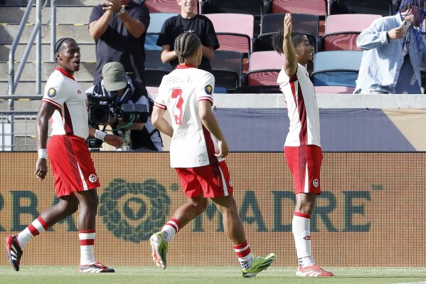 Canada's Nathan Saliba, right, celebrates his goal against Curaca in front of Jonathan David, left, and Zorhan Bassong (3) during a CONCACAF Gold Cup soccer match Saturday, June 21, 2025, in Houston, Texas. (AP Photo/Michael Wyke)