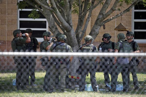 FILE - Law enforcement personnel stand outside Robb Elementary School following a shooting, May 24, 2022, in Uvalde, Texas. When the gunman arrived at the school, he hopped its fence and easily entered through an unlocked back door, police said. He holed himself up in a fourth-grade classroom where he killed the children and teachers. (AP Photo/Dario Lopez-Mills, File)