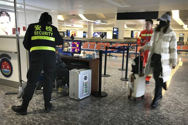 A traveler passes through a health screening checkpoint at Wuhan Tianhe International Airport in Wuhan in southern China's Hubei province, Tuesday, Jan. 21, 2020. A fourth person has died in an outbreak of a new coronavirus in China, authorities said Tuesday, as more places stepped up medical screening of travelers from the country as it enters its busiest travel period. (AP Photo/Emily Wang)
