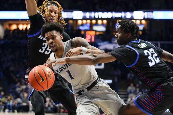 Xavier guard Paul Scruggs (1) has the ball knocked out by DePaul's David Jones (32) during the first half of an NCAA college basketball game, Saturday, Feb. 5, 2022, in Cincinnati. (AP Photo/Jeff Dean)