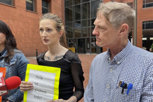 Amanda Householder, center, speaks outside the St. Louis office of Missouri Attorney General Andrew Bailey on Monday, May 13, 2024, as David Clohessy, right, listens. They were among a group of people urging Bailey to take action in response to allegations of child abuse at Christian boarding schools in southern Missouri. (AP Photo/Jim Salter)