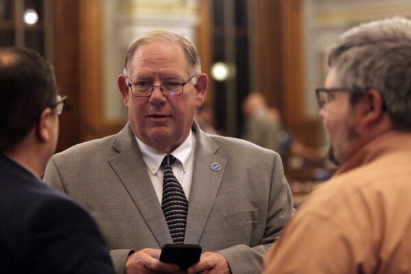 Kansas House Speaker Dan Hawkins, R-Wichita, confers with other House members during a break in the chamber's daylong session at the Statehouse, Tuesday, April 30, 2024, in Topeka, Kan. Hawkins is calling Democratic Gov. Laura Kelly's veto of a plan for cutting taxes and promise to call legislators into special session "spiteful." (AP Photo/John Hanna)