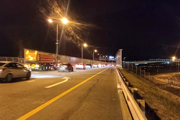In this photo taken from a video released by Press Service of Russian Deputy Prime Minister Marat Khusnullin, cars drive tore XAZ the Crimean Bridge connecting Russian mainland and Crimean peninsula over the Kerch Strait after opening a reverse traffic in Krasnodar region of south Russia on Tuesday, July 18, 2023. Traffic on the automobile part of the bridge was restored after midnight, the first cars went along the extreme right lane of the Taman-Kerch direction. While traffic is allowed only for cars, trucks are still transported through the ferry crossing. (Press Service of Russian Deputy Prime Minister Marat Khusnullin via AP)