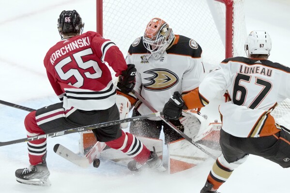 Anaheim Ducks goaltender Lukas Dostal, center, makes a stick-save against a shot by Chicago Blackhawks' Kevin Korchinski (55) as Ducks' Tristan Luneau (67) watches during the second period of an NHL hockey game Thursday, Dec. 7, 2023, in Chicago. (AP Photo/Charles Rex Arbogast)