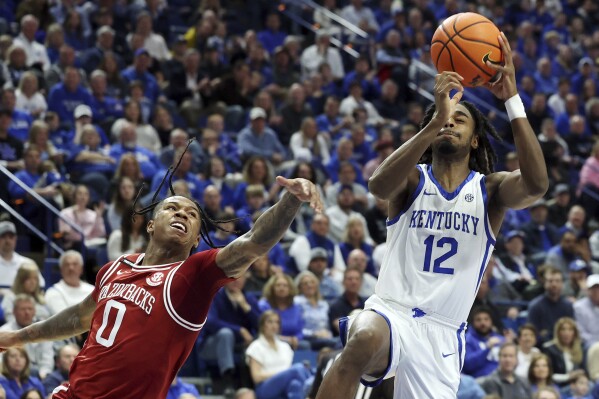 Kentucky's Antonio Reeves (12) shoots while defended by Arkansas' Khalif Battle (0) during the second half of an NCAA college basketball game Saturday, March 2, 2024, in Lexington, Ky. (AP Photo/James Crisp)