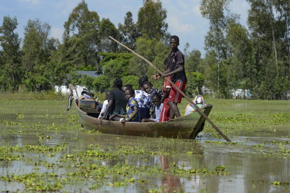 FILE - A family uses a canoe after fleeing floodwaters that wreaked havoc in Ombaka Village, Kisumu, Kenya, April 17, 2024. The impact of the calamitous rains that struck East Africa from March to May was intensified by a mix of climate change and rapid growth of urban areas, an international team of climate scientists said in a study. (AP Photo/Brian Ongoro, File)