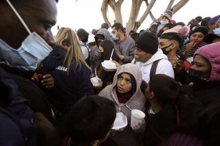 En esta imagen de archivo, tomada el 19 de febrero de 2021, solicitantes de asilo reciben comida mientras esperan noticias sobre los cambios de la política migratoria estadounidense en la frontera, en Tijuana, México. (AP Foto/Gregory Bull, archivo)