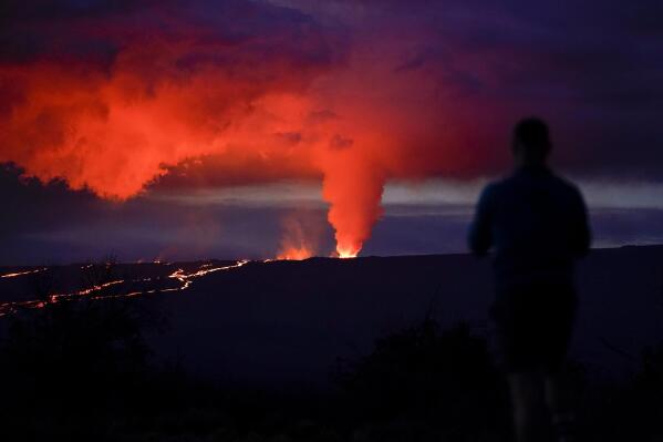 A man looks on as lava erupts from Hawaii's Mauna Loa volcano Wednesday, Nov. 30, 2022, near Hilo, Hawaii. (AP Photo/Gregory Bull)