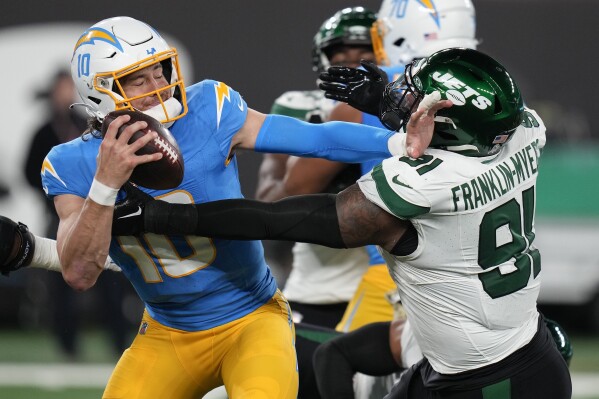 Los Angeles Chargers quarterback Justin Herbert (10) stiff-arms New York Jets defensive end John Franklin-Myers (91) during the second quarter of an NFL football game, Monday, Nov. 6, 2023, in East Rutherford, N.J. (AP Photo/Seth Wenig)