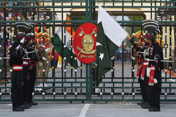 Pakistan's Rangers soldiers, in black, and Indian Border Security Forces soldiers, lower their flags during a daily closing ceremony at the Wagah, a joint post on the Pakistan and India border, near Lahore, Pakistan, Saturday, May 3, 2025. (AP Photo/K.M. Chaudary)