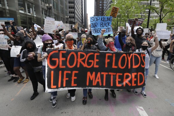 FILE - Protesters hold signs as they march during a protest over the death of George Floyd in Chicago, May 30, 2020. Minneapolis must enact police reforms in the wake of George Floyd's murder under a settlement agreement with the state Human Rights Department approved by a local judge Thursday, July 13, 2023. (AP Photo/Nam Y. Huh, File)