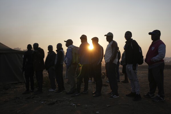 Voters wait in a queue to cast their votes at a polling station in Harare, Zimbabwe, Wednesday, Aug. 23, 2023. Polls have opened in Zimbabwe as President President Emmerson Mnangagwa seeks a second and final term in a country with a history of violent and disputed votes. (AP Photo/Tsvangirayi Mukwazhi)