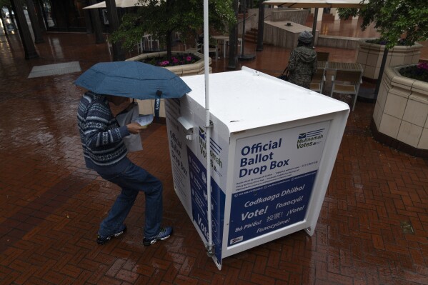 A person drops off their vote-by-mail ballot at a dropbox in Pioneer Square during primary voting on Tuesday, May 21, 2024, in Portland, Ore. (AP Photo/Jenny Kane)