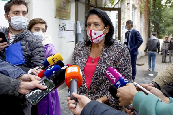 Georgia's President Salome Zurabishvili, center, wearing a face mask to help curb the spread of the coronavirus, speaks to journalists at a polling station during national municipal elections in Tbilisi, Georgia, Saturday, Oct. 2, 2021. Former President Mikheil Saakashvili was arrested after returning to Georgia, the government said Friday, a move that came as the ex-leader sought to mobilize supporters ahead of the national municipal elections seen as critical to the country's political makeup. The elections started Saturday. (AP Photo/Shakh Aivazov)