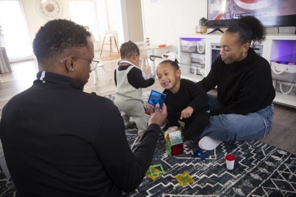 Kenneth Rioland, left, and Daizha Rioland play with their daughters, 9-month-old Izabella and Alani, 2, at their home on Saturday, Feb. 17, 2024, in Dallas. The family has struggled to find quality child care for their first daughter. (Juan Figueroa/The Dallas Morning News via AP)