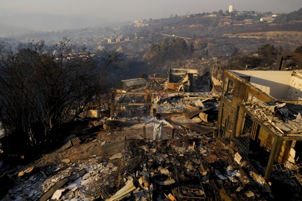A person looks at a burned-out house after a forest fire reached Villa Independencia neighborhood in Vina del Mar, Chile, Saturday, Feb. 3, 2024. (AP Photo/ Esteban Felix)