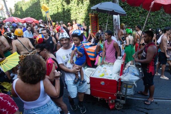 Revelers mill about as vendors with coolers filled with ice cold drinks wait for customers at the Heaven on Earth pre-Carnival street party, in Rio de Janeiro, Saturday, Feb. 22, 2025. (AP Photo/Bruna Prado)