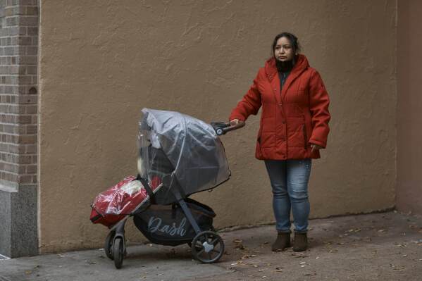 Migrant Karina Obando, from Ecuador poses for a portrait in front of the Row Hotel that serves as migrant shelter together with her 3-year-old daughter Maily Caiza on Tuesday, Dec. 12, 2023, in New York. Obando who lives with Maily, and her 11-year-old son Efren, in the Row Hotel that serves as migrant shelter, has received an eviction notice. (AP Photo/Andres Kudacki)