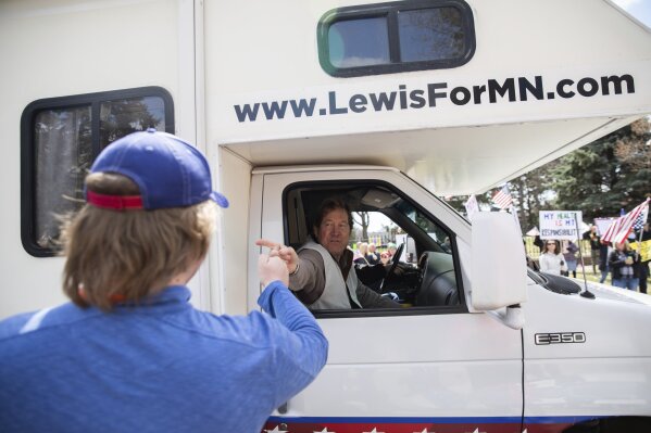 Republican U.S. Senate candidate Jason Lewis fist bumps and shakes hands with protesters from his RV during a "Liberate Minnesota" protest in St. Paul, Minn., on Friday, April 17, 2020. A growing number of protests are being staged across the U.S. to oppose stay-at-home orders amid the coronavirus pandemic. (Evan Frost/Minnesota Public Radio via AP)