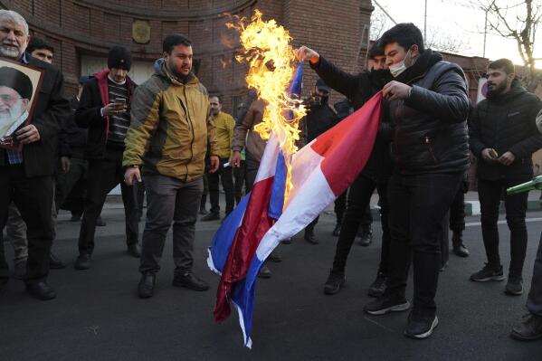 Iranian demonstrators set fire to French flags during their gathering to protest against the publication of offensive caricatures of the Iranian Supreme Leader Ayatollah Ali Khamenei in the French satirical magazine Charlie Hebdo, in front of the French Embassy in Tehran, Iran, Sunday, Jan. 8, 2023. (AP Photo/Vahid Salemi)