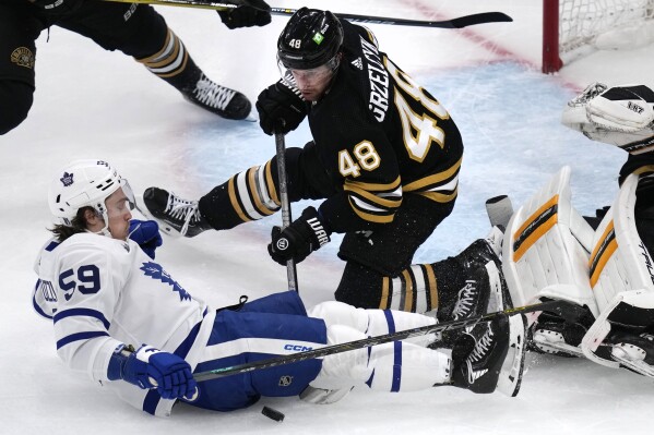 Boston Bruins defenseman Matt Grzelcyk (48) tries to free the puck as Toronto Maple Leafs left wing Tyler Bertuzzi (59) drops to the ice during the second period of Game 5 of an NHL hockey Stanley Cup first-round playoff series, Tuesday, April 30, 2024, in Boston. (AP Photo/Charles Krupa)