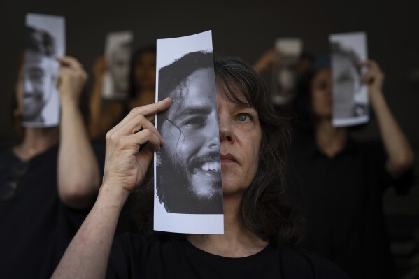 Relatives and supporters of Israeli hostages held by Hamas in Gaza hold photos of their loved ones during a performance calling for their return in Tel Aviv, Israel, Thursday, May 23, 2024. (AP Photo/Oded Balilty)