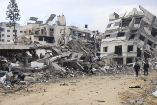 Palestinians walk past the building destroyed in the Israeli Bombardment of the Gaza Strip in Gaza City on Wednesday, Jan. 3, 2024. (AP Photo/Mohammed Hajjar)