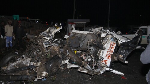CORRECTS DATE - People standing near the wreckage of vehicles after a fatal accident in Lodiani, Kenya, Friday, June 30, 2023, at a location known for crashes about 200 kilometers (125 miles) northwest of the capital, Nairobi.  Dozens were killed when a truck rammed into several other vehicles and market traders on Friday evening, police said.  (AP Photos)