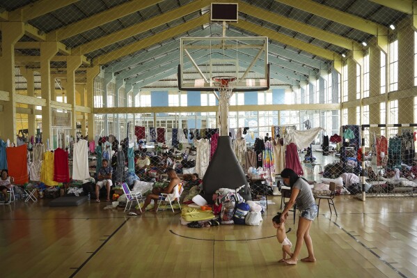 Residents rest in a gymnasium converted into a shelter for people whose homes were flooded by torrential rains, in Canoas, Rio Grande do Sul state, Brazil, May 8, 2024. (AP Photo/Carlos Macedo)