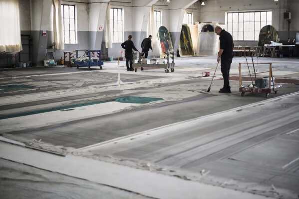 Set designers work on a stage canvas in the "Teatro dell' Opera" opera house warehouse, in Rome, Thursday, April 10, 2025. (AP Photo/Andrew Medichini)