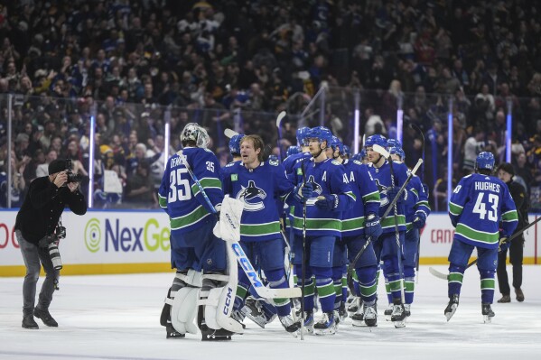 Vancouver Canucks' Brock Boeser, third from left, celebrates after his winning goal with goalie Thatcher Demko (35) during overtime NHL hockey game action against the Boston Bruins in Vancouver, British Columbia, Saturday, Feb. 24, 2024. (Darryl Dyck/The Canadian Press via AP)