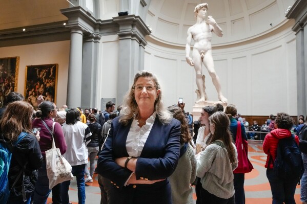 FILE-- Cecilie Hollberg, director of the Accademia Gallery poses in front of Michelangelo's white marble statue "David" in Florence, Italy, in this Tuesday, March 28, 2023 file photo. The German director of Florence's Accademia Gallery has achieved her goal of drawing visitors' attention to masterpieces beyond Michelangelo's towering David. Hollberg is celebrating her achievements at Italy's second-most visited museum since arriving in 2015, even rumors circulate that Italy's right wing government intends to send her packing before her contract expires next year as it seeks to put more Italians in top cultural jobs. (AP Photo/Alessandra Tarantino)