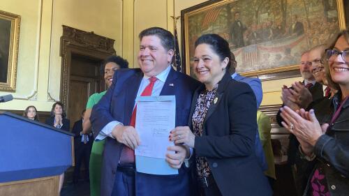 Illinois Gov. J.B. Pritzker, center left, and Comptroller Susana Mendoza smile at the state Capitol, in Springfield, Ill., Wednesday, May 10, 2023, after Pritzker signed a law providing disability benefits to Chicago first responders, including Mendoza's brother, who contracted COVID-19 on the job before vaccines were available. Pritzker said he was not worried about a $1.84 billion drop in revenue in April compared with a year earlier because the budget he proposed last winter for the fiscal year that begins July anticipated less revenue. The Legislature has to approve a spending plan before its scheduled spring session adjournment on Friday, April 19. (AP Photo/John O'Connor)