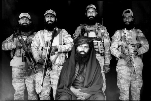 Taliban commander Mazlumyar, 32, center, poses for a portrait with security guards who work for the Migration department, after the distribution of food rations for women by a humanitarian aid group, in Kabul, Afghanistan, Sunday, May 28, 2023. (AP Photo/Rodrigo Abd)
